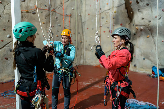 Women practice vertical caving rope techniques in gym