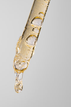 Golden cosmetic serum in glass pipette with air bubble