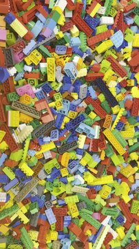 A colorful pile of plastic building blocks scattered in a random mix, showing many shapes and bright toy pieces from above lego