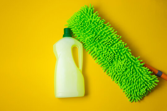 Floor cleaner bottle and microfiber mop on color background