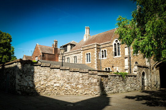 Dramatic view of an ancient, stone and brick building now used as a retail store seen in the historic cathedral city of Ely, UK. Note the heavy shadows, caused by the nearby cathedral, towards the lef