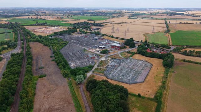 Panning aerial view of large 400kV National Grid electrical substation switchyard with high voltage busbars near Newark