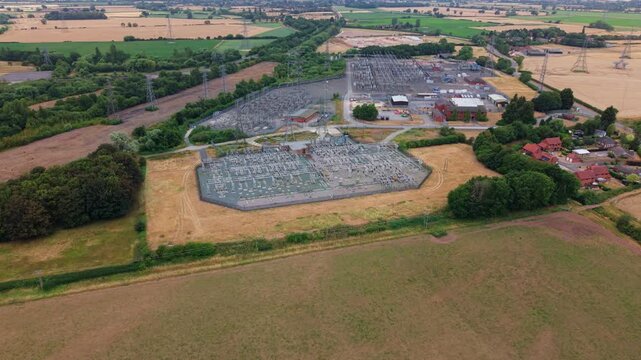 Panning aerial view of large 400kV National Grid electrical substation switchyard with high voltage busbars near Newark