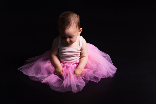 Baby girl wearing a pink tutu on dark background