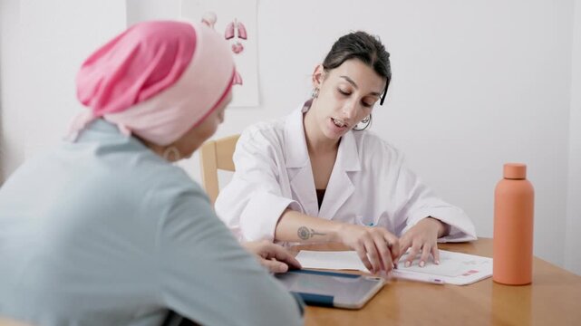 Young female doctor prescribing treatment to cancer patient