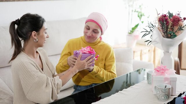 Daughter giving a gift to mother with cancer during celebration
