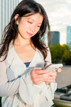 Gen z Chinese woman using smartphone on city walkway