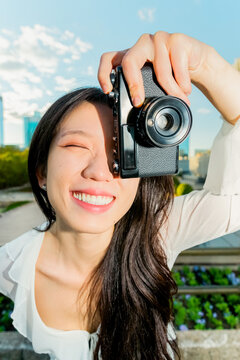 Gen Z Chinese woman taking a photo with a vintage camera