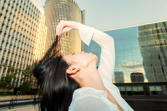 Gen Z Chinese woman stretching outdoors in modern city