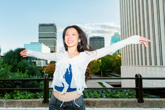 Happy gen z Chinese woman stretching arms in city park