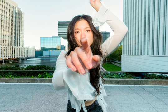 Gen z Chinese woman pointing at camera in modern city