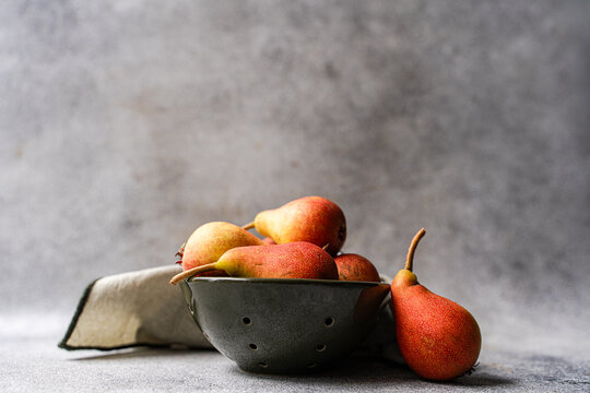 Ripe pear fruit in colander on rustic gray background
