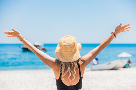Woman raise arms on sunny tropical beach vacation