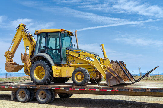 Utah, USA - June 30, 2026: A John Deere 310 G-Tier Backhoe Loader secured on a flatbed trailer
