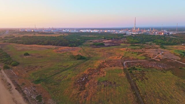 Oil refinery and green landscape in Sines, Portugal at sunset. Aerial view, distant shot. Moving forward