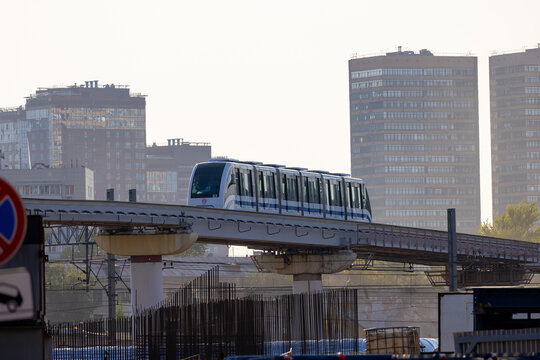 Moscow Monorail train number 03 moves along an elevated road against a backdrop of high-rise residential buildings. Public transportation system in the city. Russia, Moscow - September 16, 2024