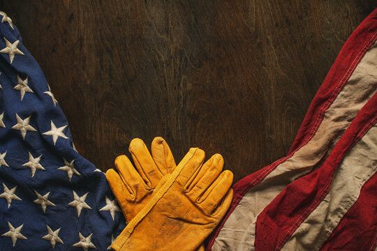Work gloves with the American flag on wooden background. Symbolic of blue collar workers, USA manufacturing, pride in products Made in United States of America, or for Father's day or US Labor Day.