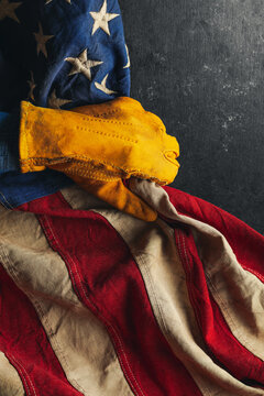 Worn work glove pulling back the American flag. Symbolic of blue collar workers, USA manufacturing, pride in products Made in United States of America, or to celebrate Father's day or US Labor Day.