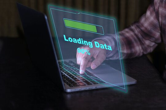 Close-up of a user downloading files, with a futuristic loading screen superimposed on the laptop displaying the message &ldquo;Loading data&rdquo;