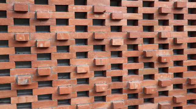 a decorative red brick wall designed with alternating perforated gaps to facilitate natural air circulation