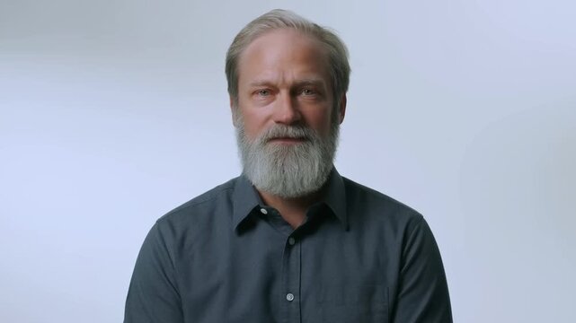Time lapse frontal portrait of man aging and growing beard in studio head and shoulders static shot with neutral background and consistent lighting