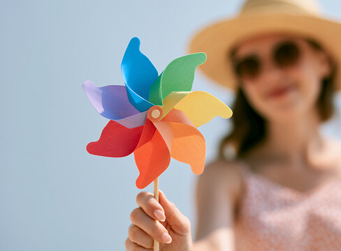 Young woman holding colorful pinwheel on sunny summer day