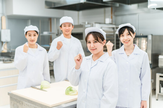 Male and female kitchen staff cutting cabbage in the kitchen and back room.