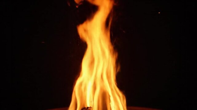 Bright orange flames dancing upwards in a dark environment creating a warm and energetic visual