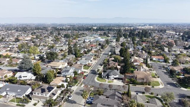 Aerial view of residential neighborhood in Cupertino, California with suburban homes and distant mountains. g.