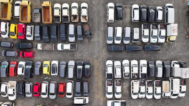 The parking lot was filled with cars lined up for rent, and there were several cars damaged in accidents parked there.