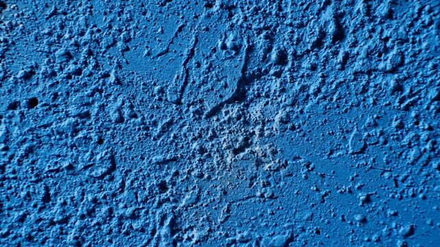 Close-up slow zoom on heavily textured blue wall revealing abstract patterns and rough surfaces