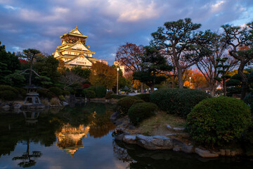 Iconic Osaka Castle by garden with skyline reflection on pond at dusk © Blanscape