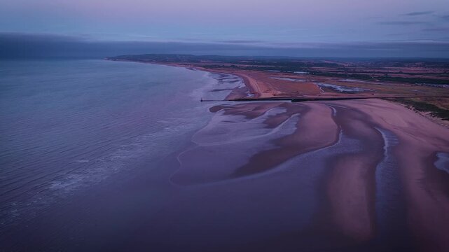 Aerial view of Camber Sands after sunrise, with shoreline, tidal sand patterns and blue sea in East Sussex; ideal for travel, tourism and coastal advertising