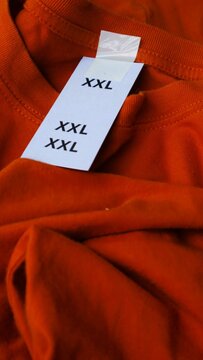 Close up of a large orange t-shirt with a size XXL label tag attached.