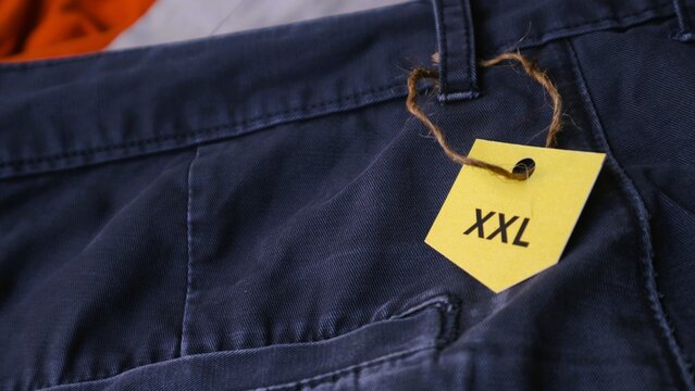 Close up of a yellow price tag showing XXL size on blue trousers.