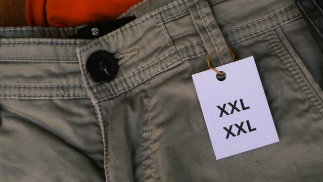 Close up of a pair of khaki pants with an XXL size tag attached.