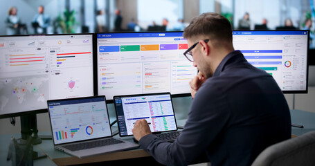 Young Businessman Studies Sales Data On Laptop