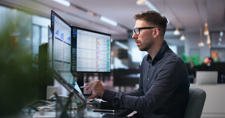 Man Analyzes Medical Billing Data On Dual Laptop Screens