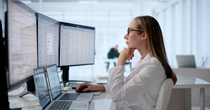 Woman At Desk Updating Patient Records On Computer