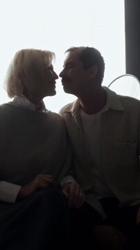 Silhouette of a loving senior couple sharing a tender moment, holding hands, and kissing against a bright white background, symbolizing eternal love, companionship, and a happy retirement