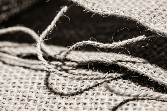 Macro of coarse burlap jute cloth with loose curling threads, rustic fabric texture