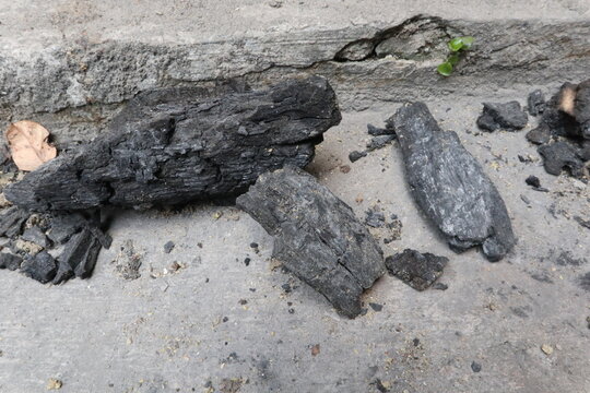 Charred wood and charcoal residue left after firewood burning in a rural village yard in Java, Indonesia. Close-up of natural fuel remnants used for cooking and household activities.