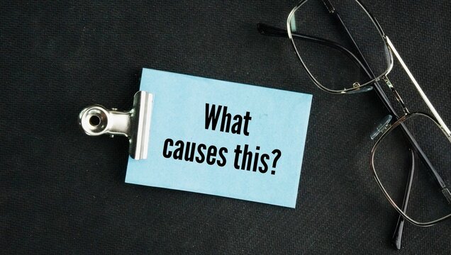 Glasses and paper with question words What causes this? asking for the specific reason, source, or trigger that makes a particular event, problem, or condition happen.