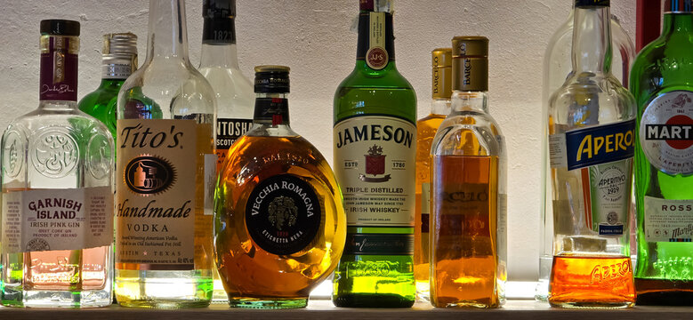 Bucharest, Romania - March 13, 2025: Close-up shot of various liquor bottles lined up on a shelf, showcasing different brands and types of alcohol. Focus on the bottles, labels, and colors.