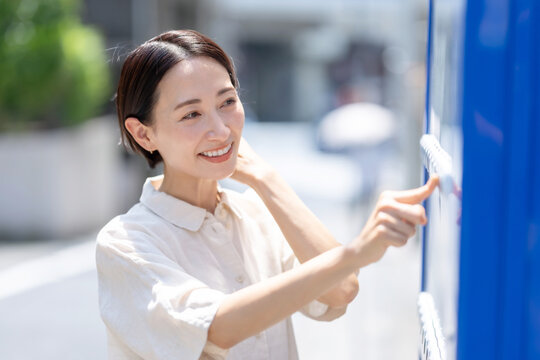自動販売機で飲み物を買う女性