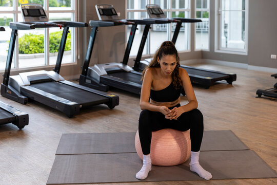 Calm young woman practicing meditation and gentle fitness exercises in a modern gym, combining mindfulness, rest and light workout for a balanced healthy lifestyle.
