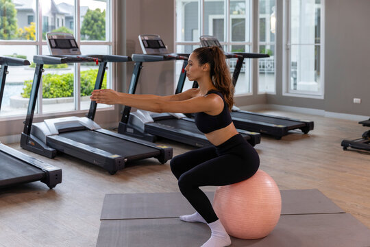 Calm young woman practicing meditation and gentle fitness exercises in a modern gym, combining mindfulness, rest and light workout for a balanced healthy lifestyle.