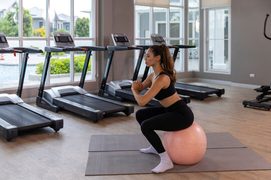 Calm young woman practicing meditation and gentle fitness exercises in a modern gym, combining mindfulness, rest and light workout for a balanced healthy lifestyle.