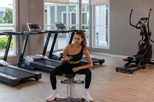 Calm young woman practicing meditation and gentle fitness exercises in a modern gym, combining mindfulness, rest and light workout for a balanced healthy lifestyle.