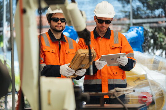 Two robotic technician testing robot welding before delivery, supporting inspection, programming, calibration, safety, quality assurance, commissioning.